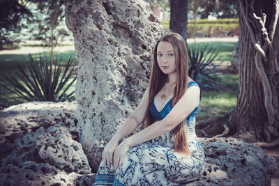 Portrait of young woman against tree trunk