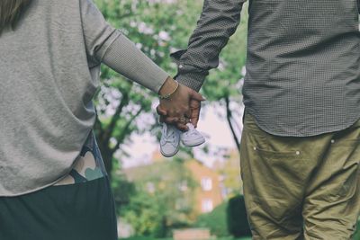 Midsection of couple holding baby shoes