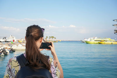 Young woman looking at sea against sky