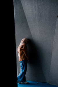 Side view of a woman walking against wall