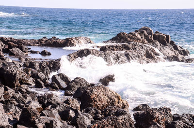 Scenic view of rocks in sea against sky