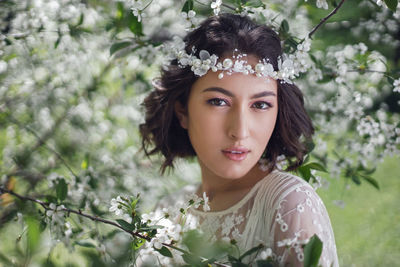 Portrait of smiling young woman standing against tree