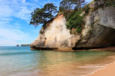 Rock formation on beach against sky