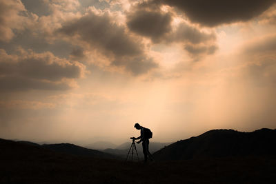 Silhouette man standing on mountain against sky during sunset