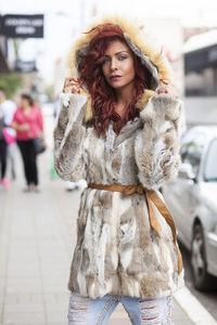 Portrait of beautiful woman in fur coat standing on city street
