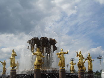 Fountain amidst statues against sky