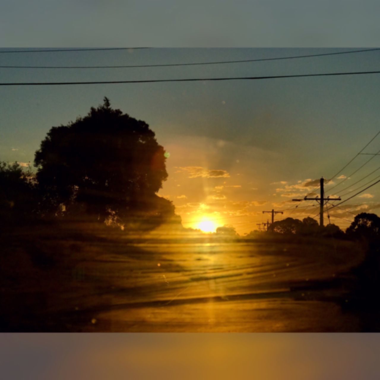 sunset, reflection, sky, tree, nature, silhouette, beauty in nature, orange color, scenics, water, outdoors, built structure, tranquil scene, no people, power supply, tranquility, building exterior, sun, electricity pylon, architecture, day