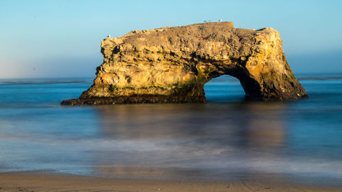 Scenic view of rock formation in sea against sky