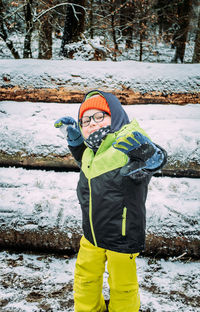Portrait of boy standing on snow covered field
