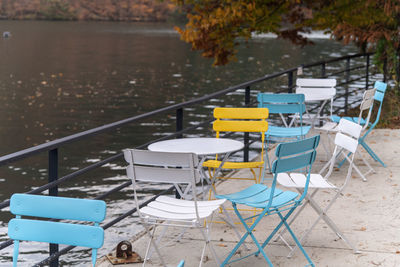 Empty chairs and tables at the lakeside during autumn