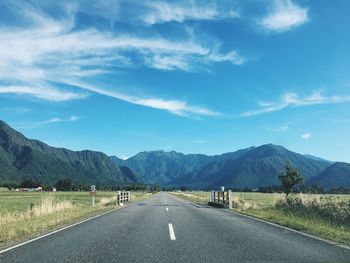 Empty road by mountains against sky