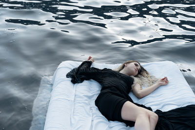 High angle view of woman lying on bed in lake