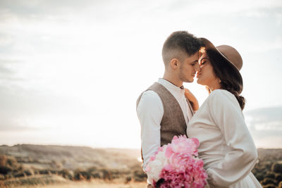 Side view of couple standing against sky