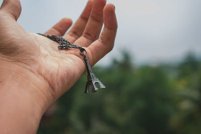 Close-up of person holding eiffel tower pendant