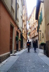 Rear view of people walking on street amidst buildings