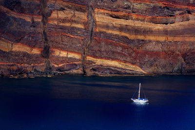 Boat on sea against rock formation