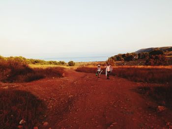 People walking on land against clear sky