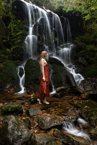 Rear view of woman standing against waterfall