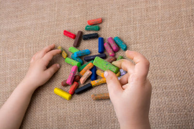 Cropped hands of child with colorful crayons at table