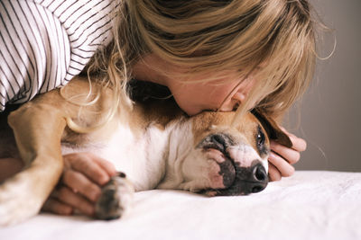 Young woman lies close to her dog und kisses her. emotional companionship lifestyle with pets