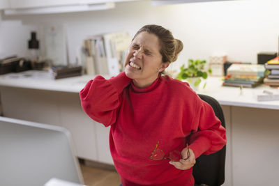 Smiling young woman standing on table at home