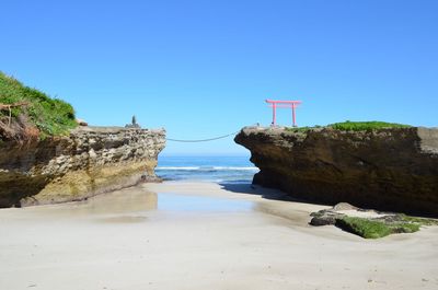 Rocks on beach against clear blue sky