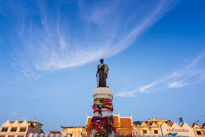 Low angle view of statue by building against sky