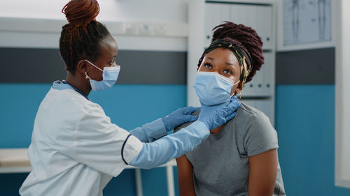 Female doctor wearing mask examining patient in clinic