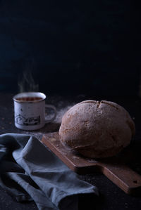 Sliced bread with jam and a cup of hot drink, on a dark background.