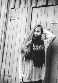 Portrait of young woman standing against wall