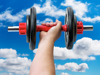 Midsection of person holding camera against sky