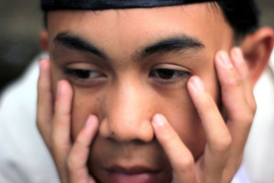 Close-up of man with hands on cheek looking away