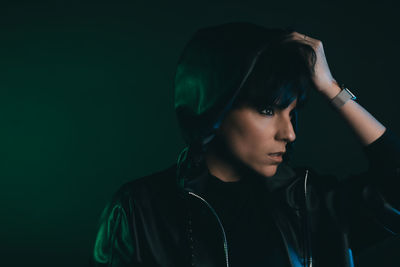 Portrait of young woman looking away against black background
