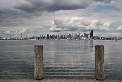 Wooden posts on pier by sea against sky