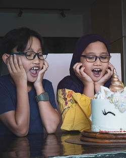 Siblings with mouth open looking at birthday cake