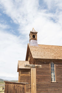 Low angle view of old church building against sky with wooden street sign in ghost town