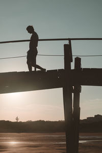 Silhouette people standing on bridge against sky during sunset