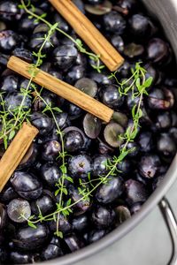 Close-up of grapes with cinnamons and rosemary in colander on table