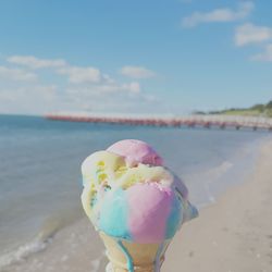 Close-up of ice cream on beach against sky