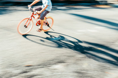 Low section of man riding bicycle on road