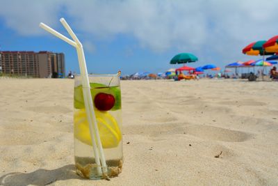 Close-up of drink on beach against sky