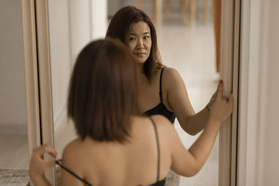 Portrait of young woman looking through window