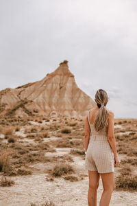 Rear view of woman standing on landscape against sky