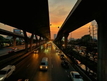 Traffic on highway in city against sky during sunset