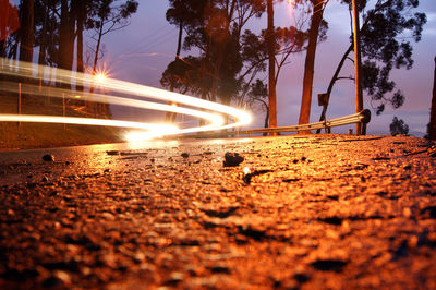 Low angle view of light trails over street at dusk