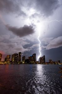 City by sea against sky at night