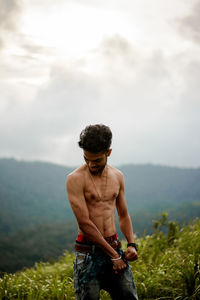 Young man standing on field against sky