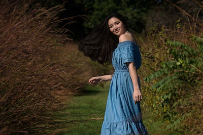 Side view portrait of teenage girl smiling while standing amidst plants