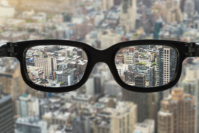 Close-up of sunglasses against buildings in city