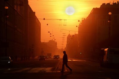 Silhouette of man in city at sunset